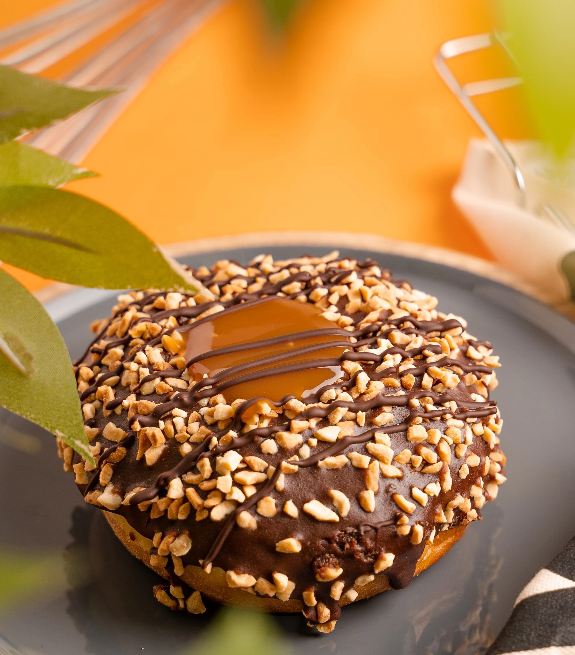 nutty doughnut with caramel center on a plate, leaves slightly in front